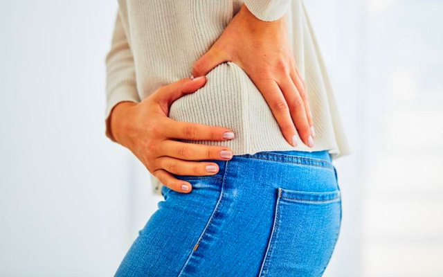 Woman holding painful hip, common symptom of hip arthritis and joint problems